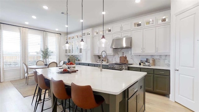 12043 Lake View Blvd, Mont Belvieu, TX 77523 - kitchen featuring under cabinet range hood, a kitchen island with sink, light countertops, tasteful backsplash, and recessed lighting