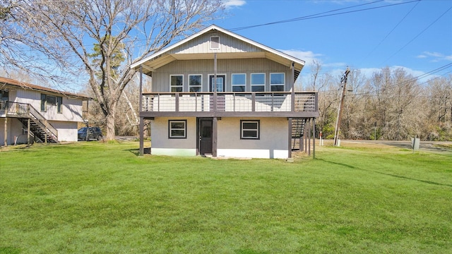 rear view of house featuring a wooden deck, stairway, a lawn, and stucco siding