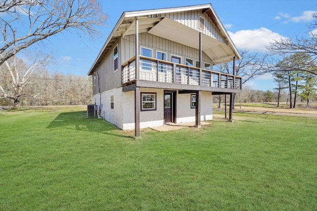 rear view of house with stucco siding, central AC, a yard, board and batten siding, and a wooden deck