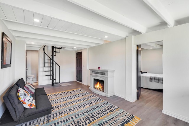 living area featuring beam ceiling, wood finished floors, recessed lighting, baseboards, and stairs