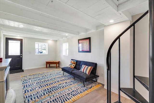 living room with beamed ceiling, light wood-style floors, and baseboards