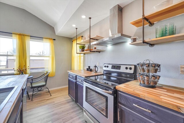kitchen with butcher block countertops, vaulted ceiling, stainless steel appliances, wall chimney exhaust hood, and open shelves