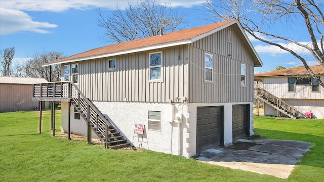 back of property with stairway, a lawn, a garage, and stucco siding