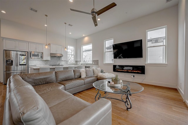 2414 Canal St Unit A, Houston, TX 77003 - living room featuring light wood finished floors, a ceiling fan, recessed lighting, a glass covered fireplace, and baseboards