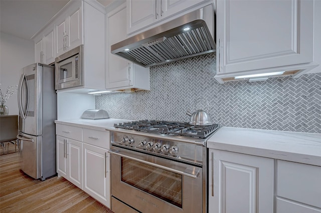 2414 Canal St Unit A, Houston, TX 77003 - kitchen featuring appliances with stainless steel finishes, under cabinet range hood, light countertops, white cabinetry, and light wood-style floors