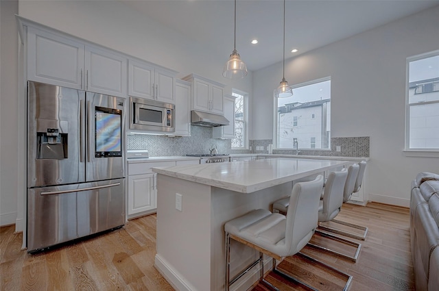 2414 Canal St Unit A, Houston, TX 77003 - kitchen with stainless steel appliances, under cabinet range hood, light wood-style flooring, white cabinetry, and recessed lighting