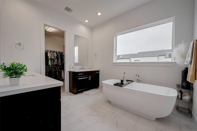 2414 Canal St Unit A, Houston, TX 77003 - bathroom featuring vanity, a freestanding tub, marble finish floors, a walk in closet, and recessed lighting