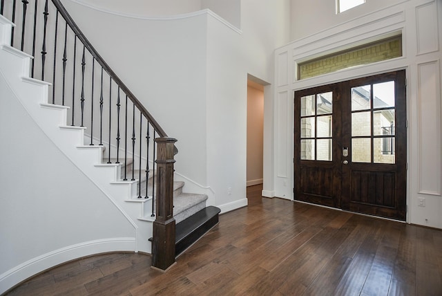 entryway featuring baseboards, stairway, a towering ceiling, and dark wood finished floors