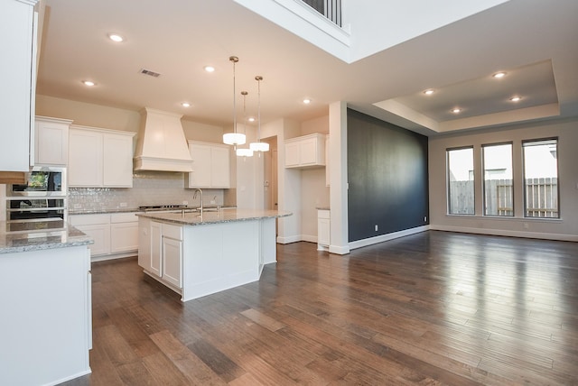 kitchen featuring dark wood finished floors, white cabinets, custom exhaust hood, stainless steel appliances, and backsplash