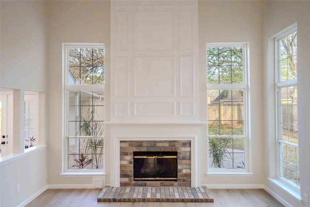 unfurnished living room featuring a fireplace, baseboards, and wood finished floors