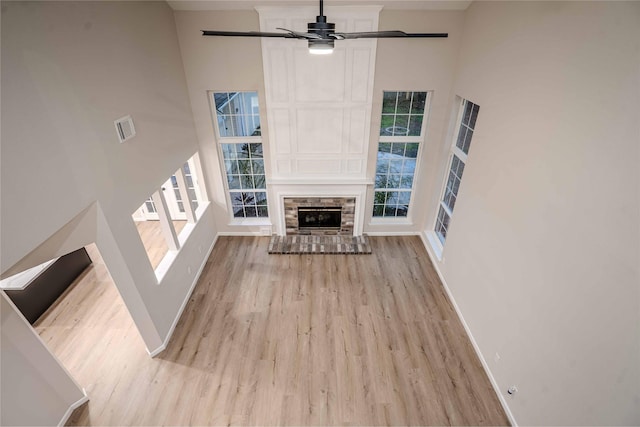 unfurnished living room featuring baseboards, light wood-style floors, a towering ceiling, and a ceiling fan