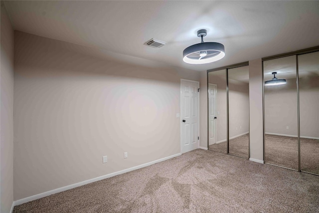unfurnished bedroom with visible vents, multiple closets, carpet, and baseboards