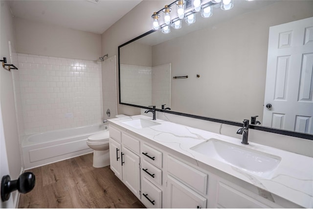 bathroom with toilet, wood finished floors, shower / bath combination, and a sink