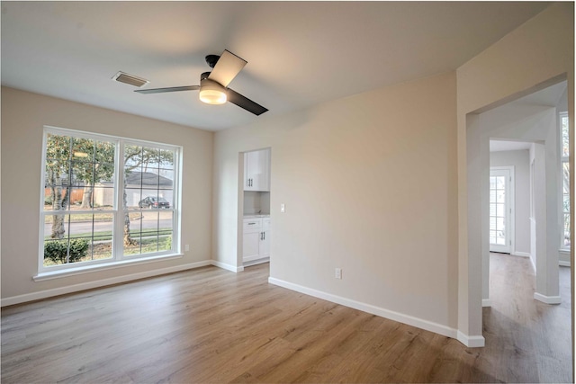 spare room with light wood-type flooring, visible vents, baseboards, and a ceiling fan