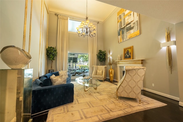 living area with ornamental molding, wood finished floors, an inviting chandelier, baseboards, and a tile fireplace