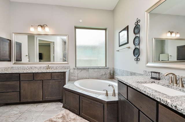 bathroom with a bath, marble finish floor, two vanities, and a sink