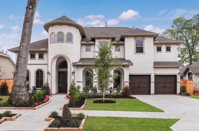 view of front of property with fence, concrete driveway, a front yard, stucco siding, and an attached garage