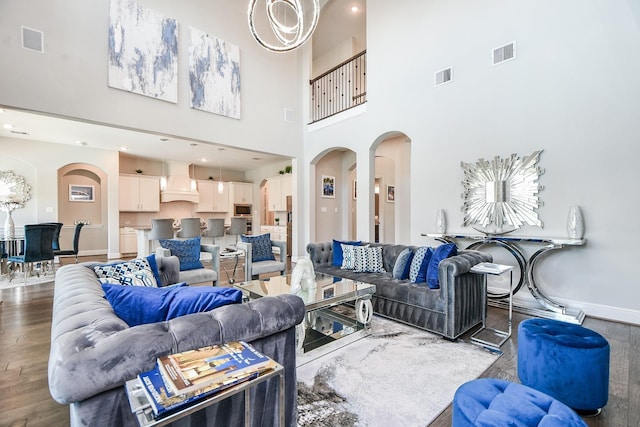 living area featuring wood finished floors, visible vents, arched walkways, and baseboards