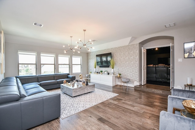 living room with a chandelier, visible vents, plenty of natural light, and dark wood-type flooring