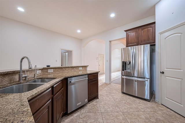 6010 Le Moyne Pass Ln, Missouri City, TX 77459 - kitchen featuring a sink, arched walkways, appliances with stainless steel finishes, and dark stone countertops