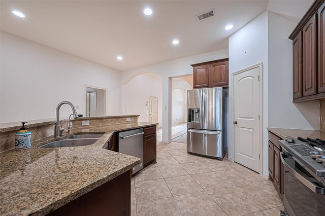 6010 Le Moyne Pass Ln, Missouri City, TX 77459 - kitchen with visible vents, a sink, arched walkways, appliances with stainless steel finishes, and stone counters