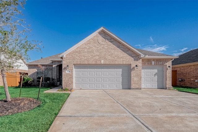 view of front of property featuring a front lawn, driveway, roof with shingles, an attached garage, and brick siding