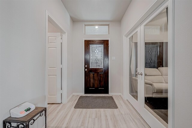 foyer with light wood-type flooring, french doors, and baseboards