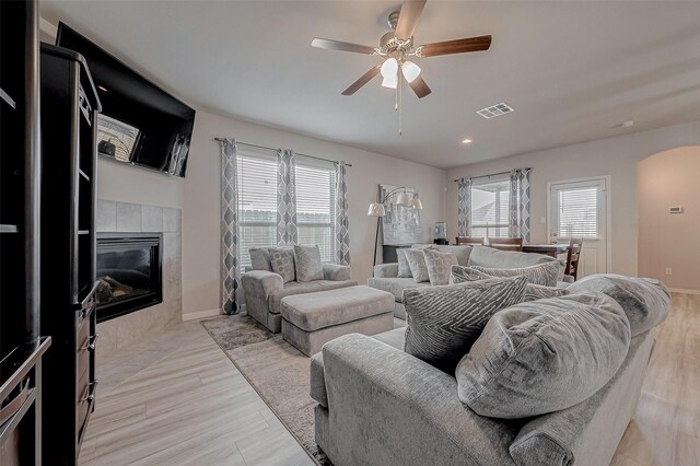 living area featuring a wealth of natural light, visible vents, ceiling fan, and a fireplace