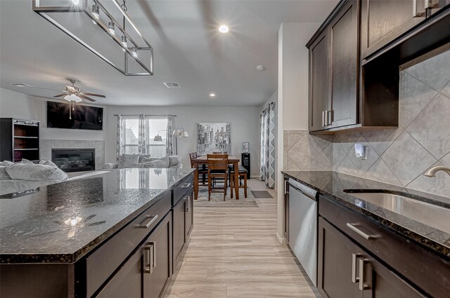 kitchen with visible vents, dark brown cabinets, ceiling fan, dishwasher, and a tile fireplace