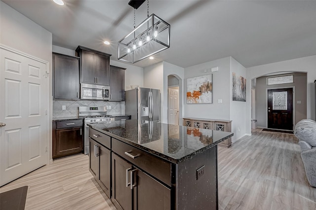 kitchen featuring arched walkways, light wood finished floors, and appliances with stainless steel finishes