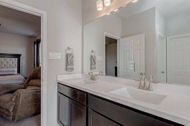 bathroom with ensuite bath, double vanity, and a sink