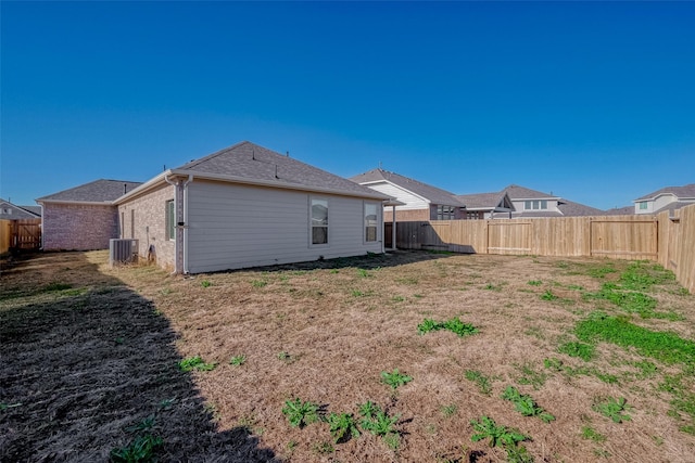 rear view of property with central AC unit and a fenced backyard