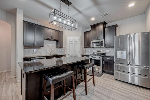 kitchen featuring visible vents, a breakfast bar area, dark stone counters, arched walkways, and stainless steel appliances