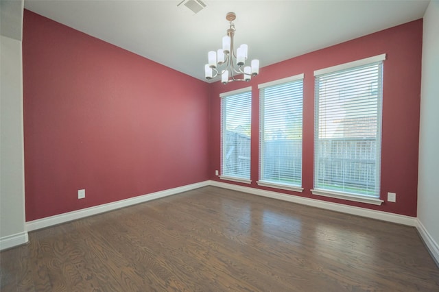 empty room with visible vents, plenty of natural light, dark wood-style floors, and a chandelier