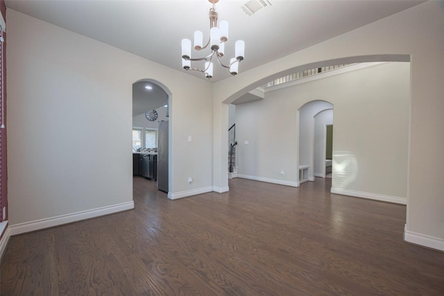unfurnished room featuring visible vents, baseboards, an inviting chandelier, arched walkways, and dark wood-style flooring