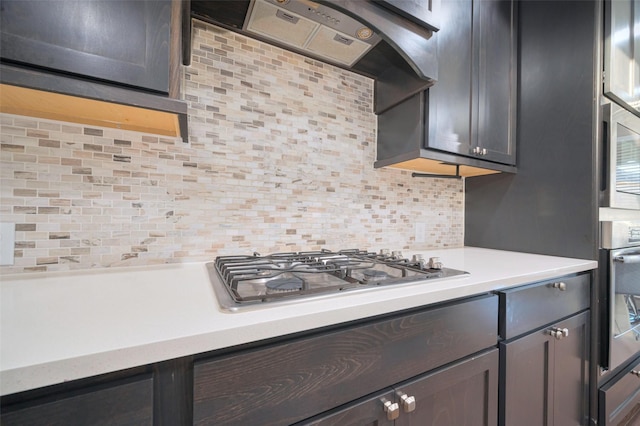 kitchen featuring tasteful backsplash, light countertops, custom range hood, appliances with stainless steel finishes, and a warming drawer