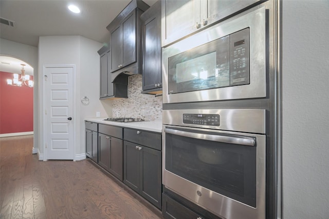 kitchen featuring tasteful backsplash, dark wood finished floors, light countertops, a notable chandelier, and stainless steel appliances