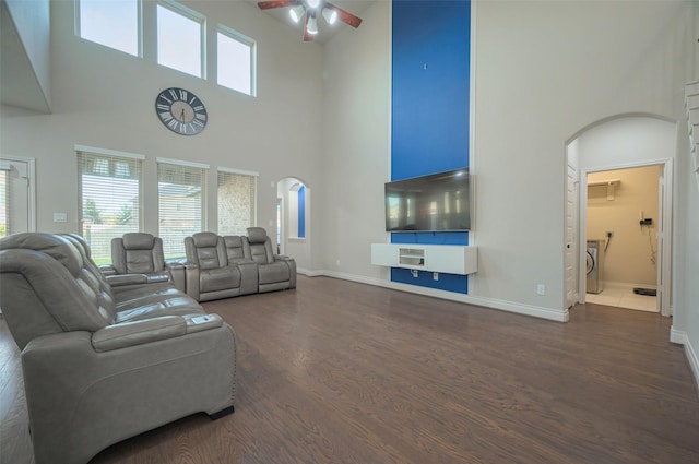 living area featuring baseboards, dark wood-style floors, washer / dryer, arched walkways, and a ceiling fan
