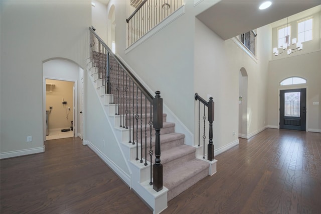 entrance foyer featuring baseboards, arched walkways, wood finished floors, and stairs