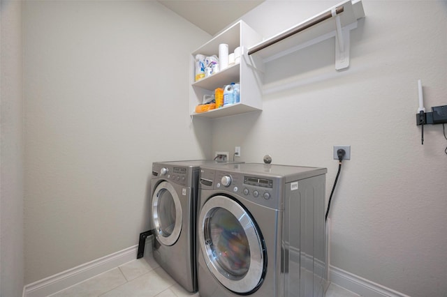 laundry room featuring light tile patterned flooring, laundry area, washing machine and dryer, and baseboards