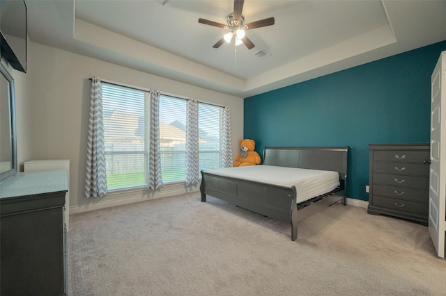 bedroom with a raised ceiling, baseboards, and light carpet