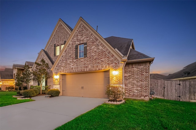 view of front of house featuring a front yard, fence, driveway, a shingled roof, and brick siding