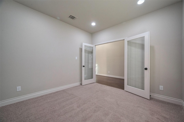 empty room featuring visible vents, carpet floors, baseboards, recessed lighting, and french doors