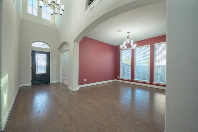 entryway featuring visible vents, baseboards, an inviting chandelier, wood finished floors, and arched walkways