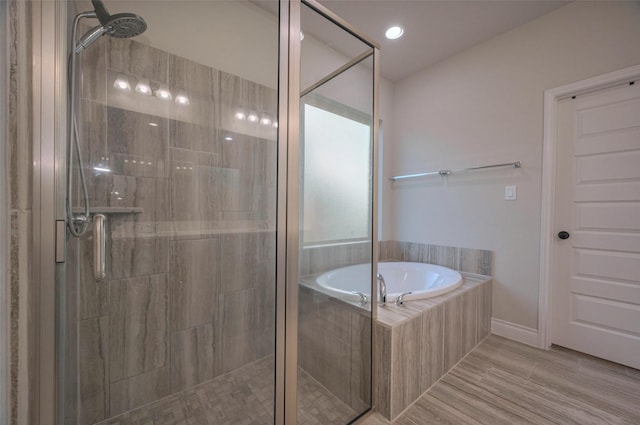 bathroom with a shower stall, a garden tub, and recessed lighting