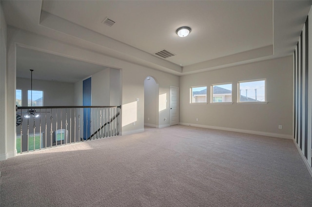 spare room with light carpet, visible vents, baseboards, and a tray ceiling