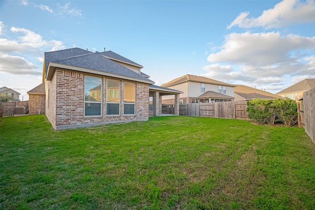back of house featuring brick siding, a lawn, and a fenced backyard