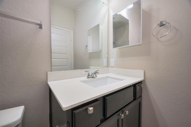 bathroom featuring toilet, vanity, and a textured wall