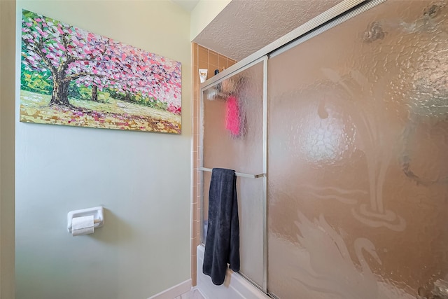 bathroom featuring a textured ceiling and a stall shower
