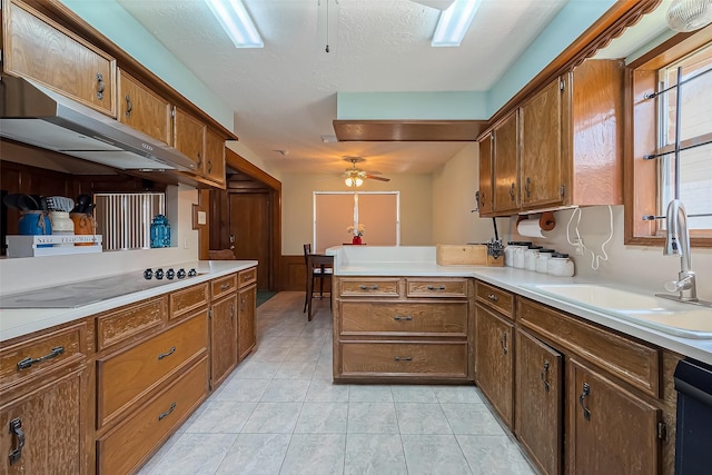 kitchen featuring ceiling fan, light countertops, a peninsula, black appliances, and a sink